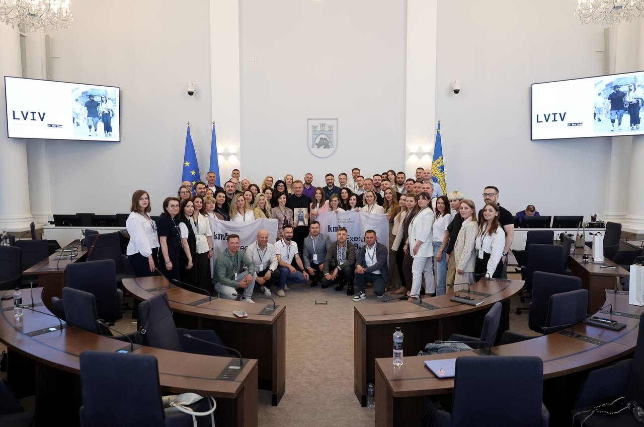 Group photo of many smiling people in a large chamber with flags and 'LVIV' on screens.